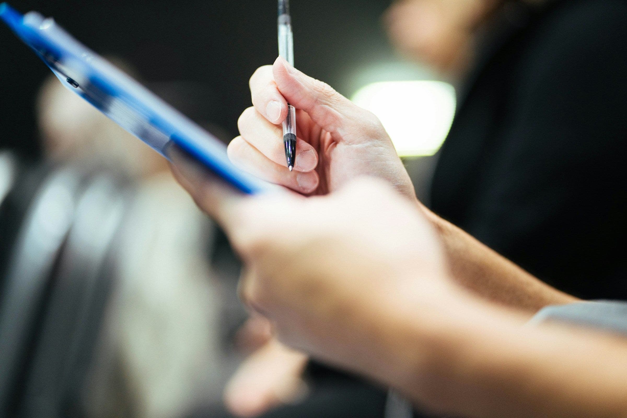 Hand holding a pen over a clipboard