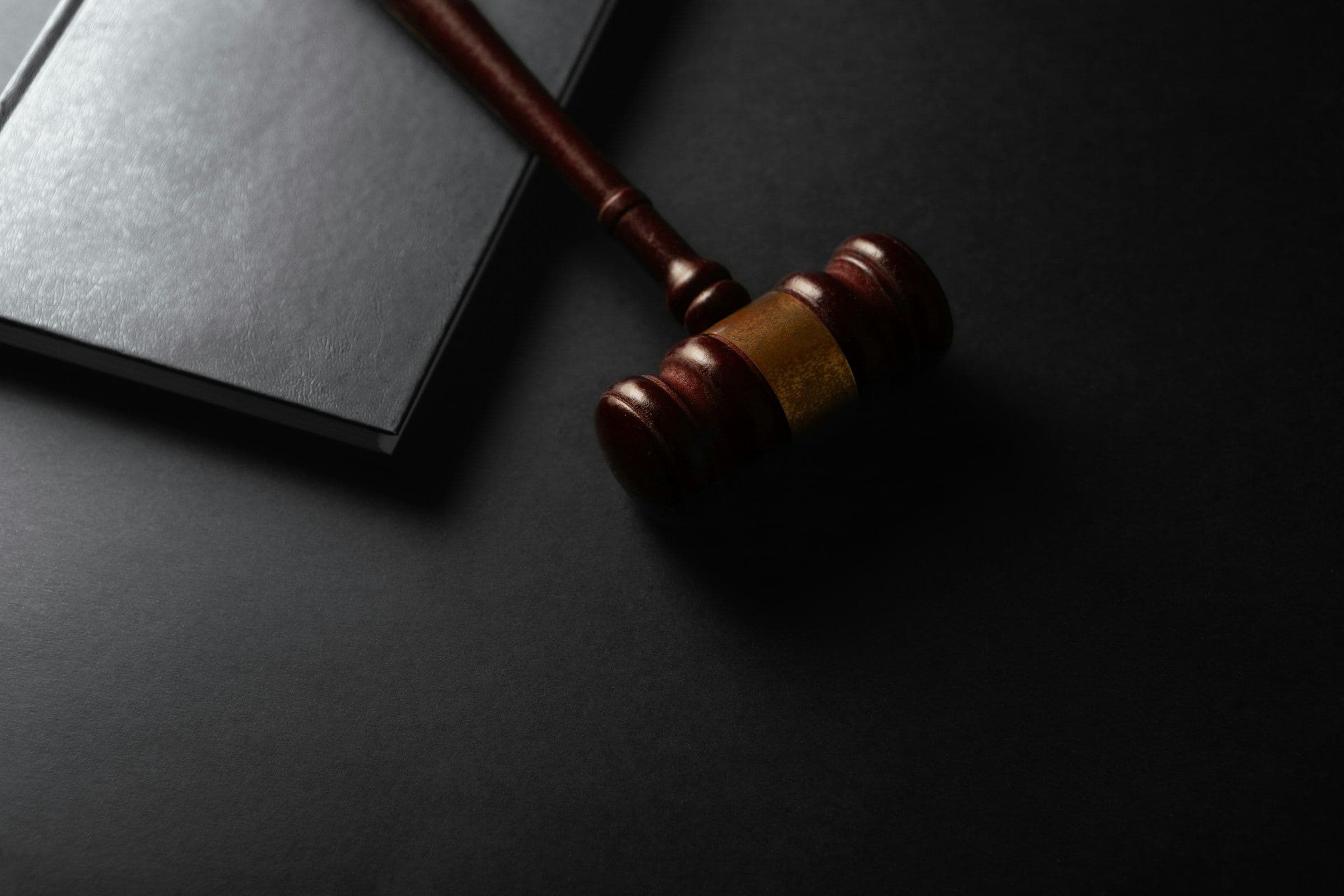 Wooden gavel beside a book on a dark surface