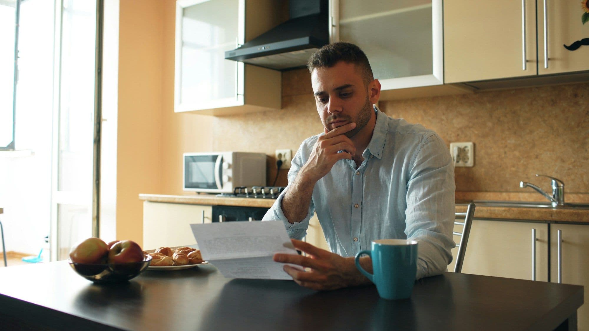 Man reading a letter at his kitchen table