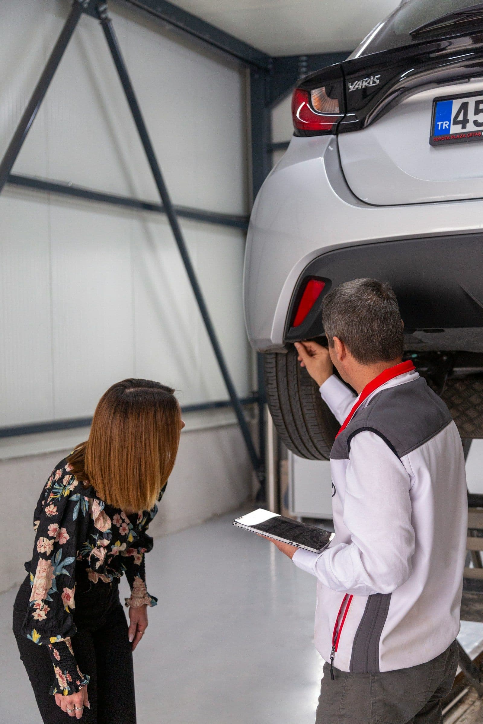 Two people inspecting the underside of a car on a lift